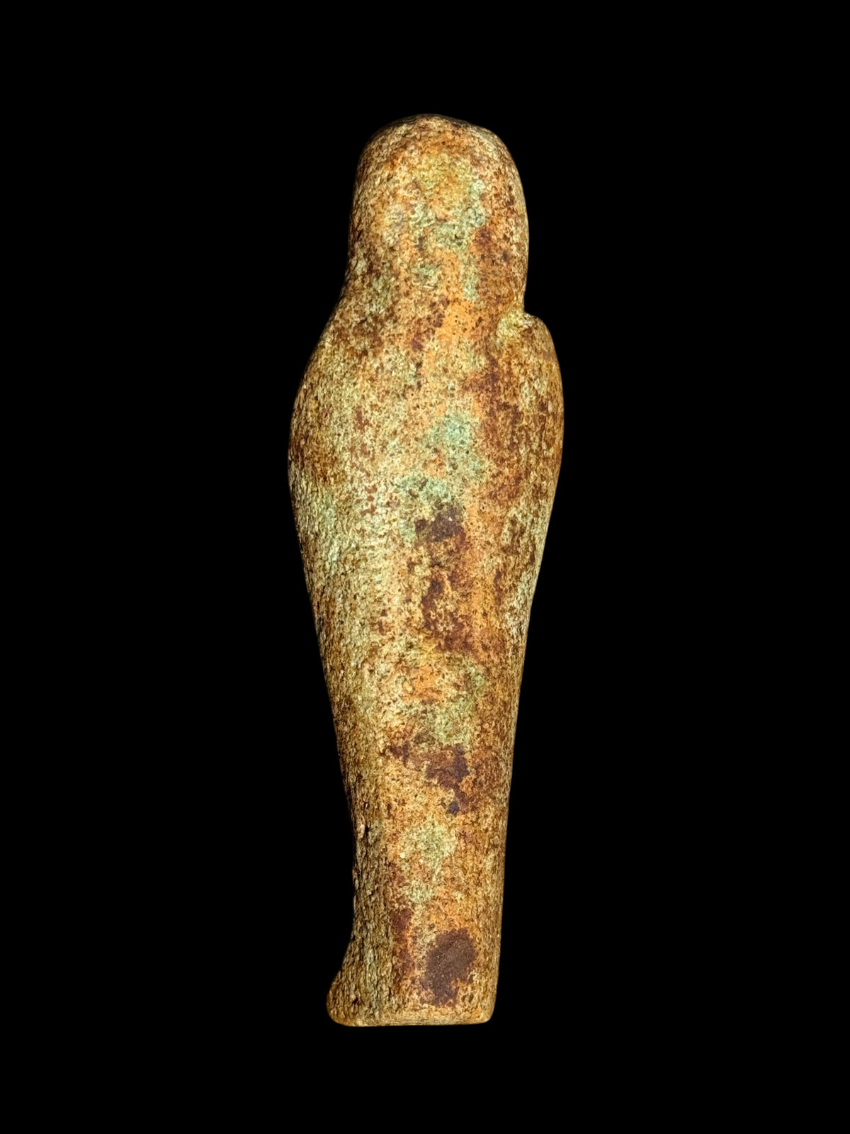 Rear view of an Egyptian stone figurine with winged Isis showing its rounded head, tapered body and textured beige, brown and muted green surface.