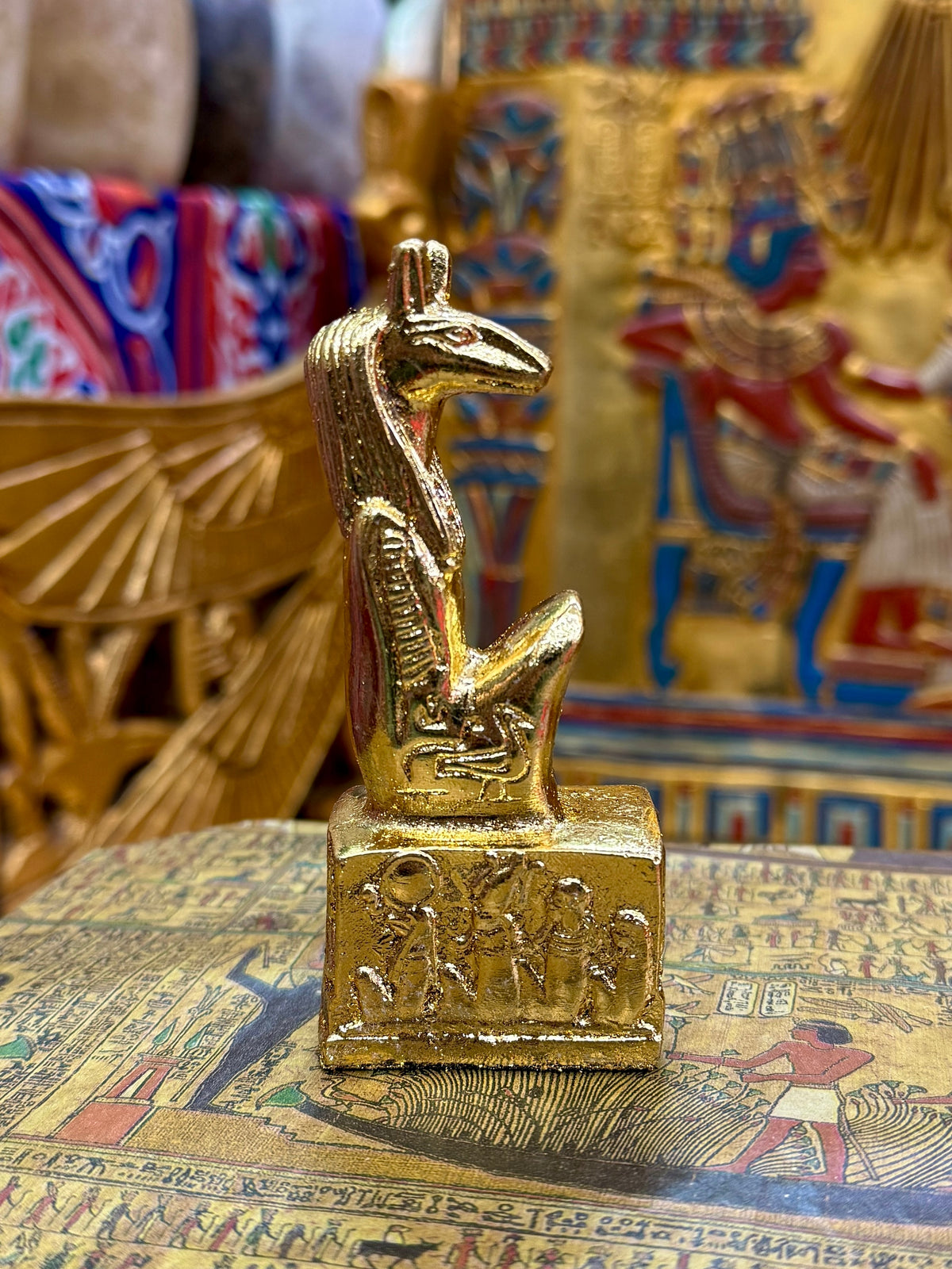 Side view of the gold finish Seth kneeling statue with long muzzle, upright ears and decorated square base.