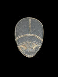 Dark grey stone scarab viewed from above, with pale incised lines outlining the wing cases and head against a black background.