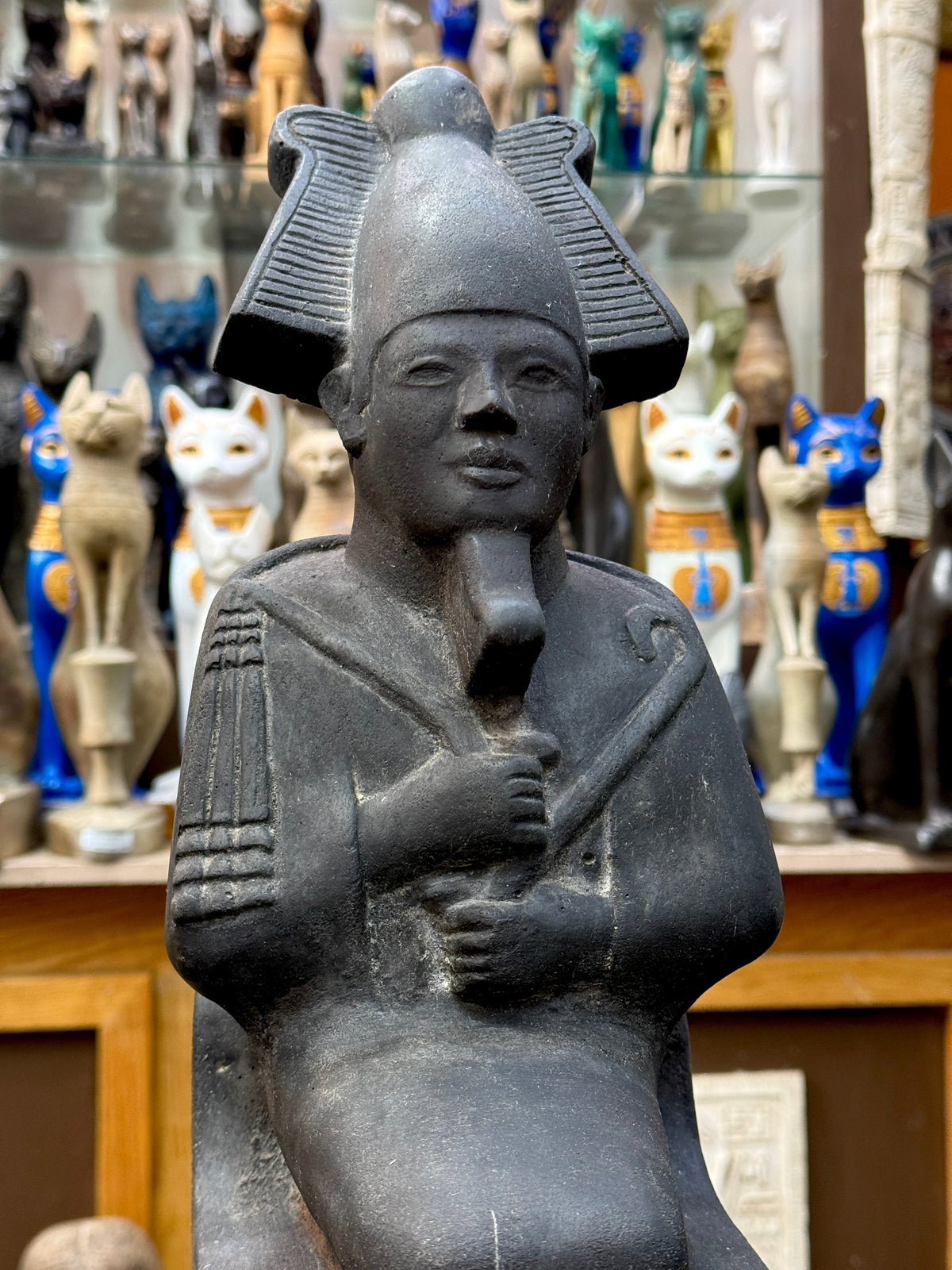 Close view of Osiris's face, feathered crown, ceremonial beard and crossed hands holding a crook and flail.