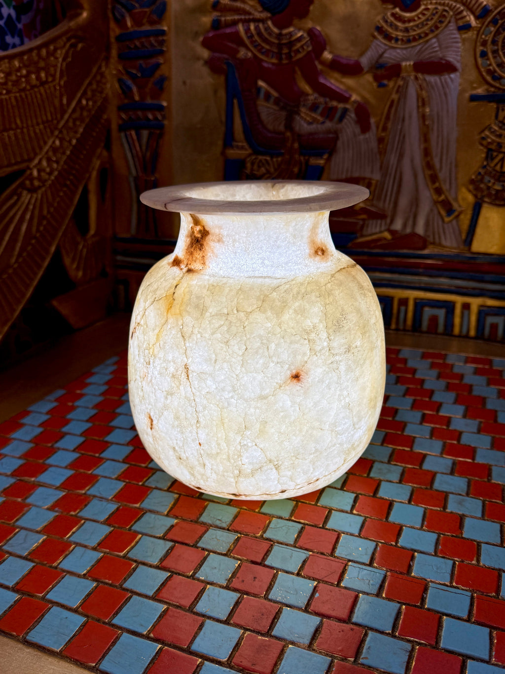 Cream alabaster vase with a rounded body, short neck, flared rim and fine golden veining — full view.