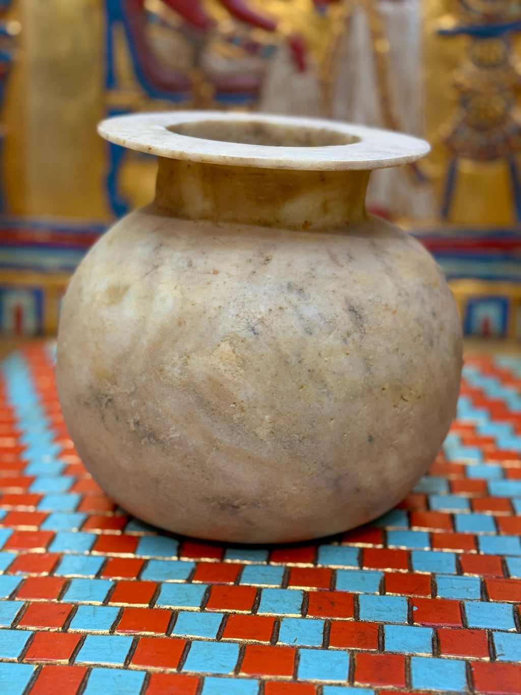 Rounded taupe and cream alabaster vase with sweeping markings, a short neck and wide flat rim — unlit full view.