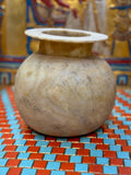 Rounded taupe and cream alabaster vase with sweeping markings, a short neck and wide flat rim — unlit full view.