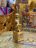 Front angled view of the gold finish Maat kneeling statue with tall feather headdress and decorated square base.