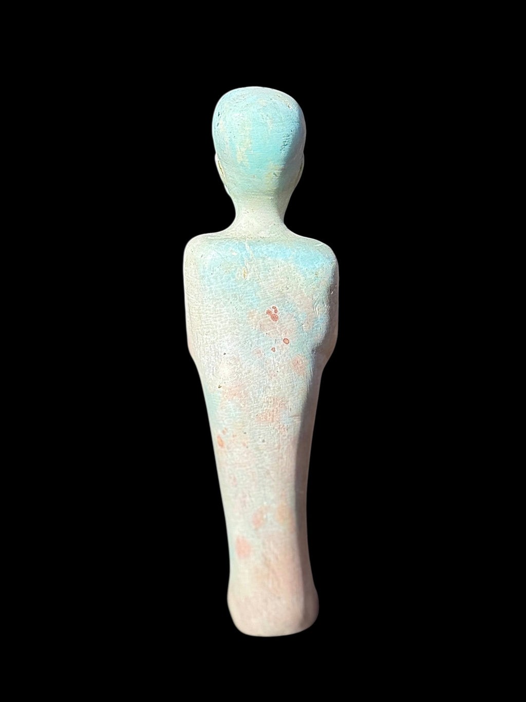 Rear view of the shabti figurine showing a plain, tapered back with mottled pale blue and cream colouring and scattered reddish patches.
