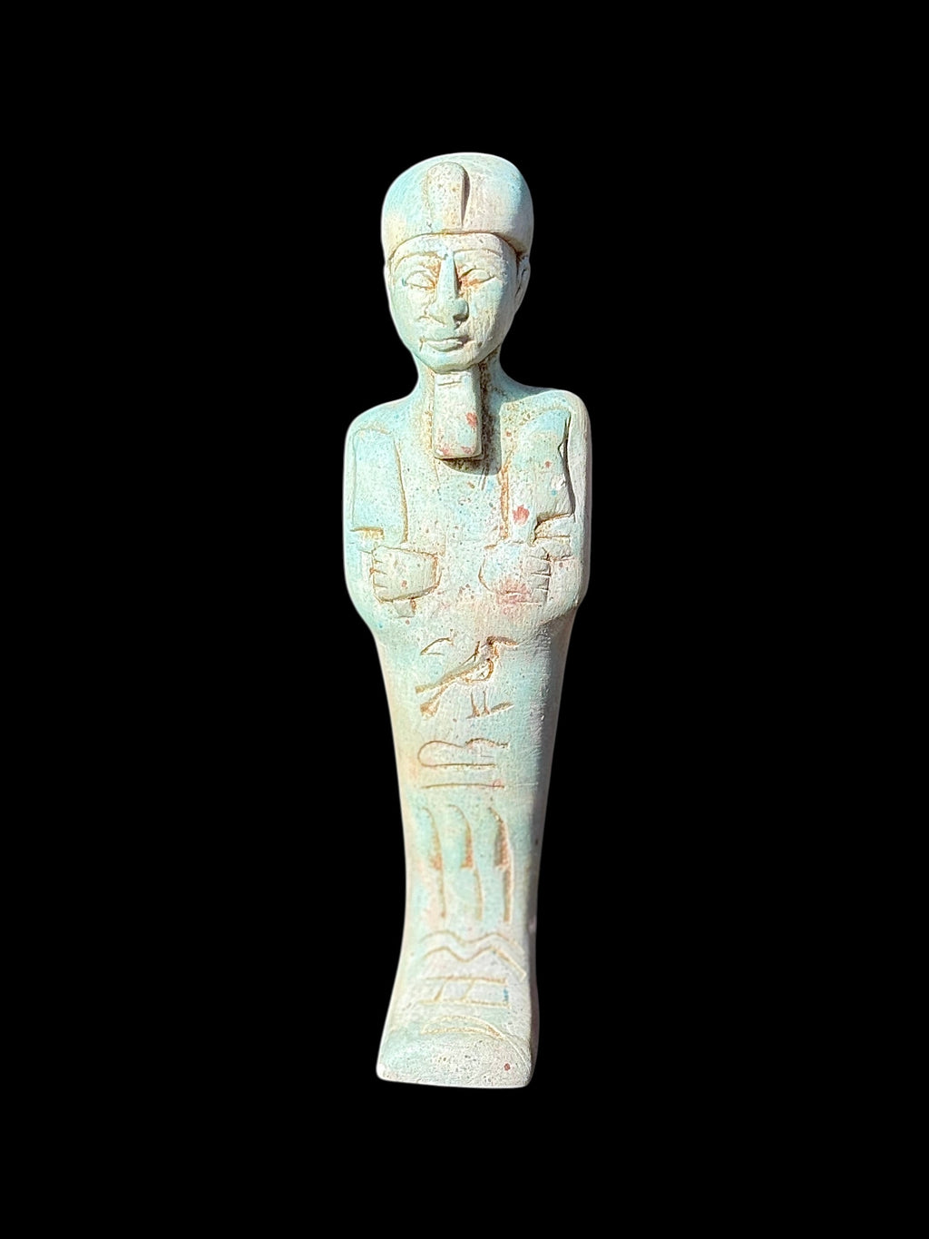 Front view of a pale blue and cream shabti figurine with rounded headdress, ceremonial beard, hands across the torso and incised markings.