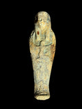Front view of an Egyptian stone figurine with a winged Isis motif, long headdress and mottled blue-green, sandy yellow and brown colouring.