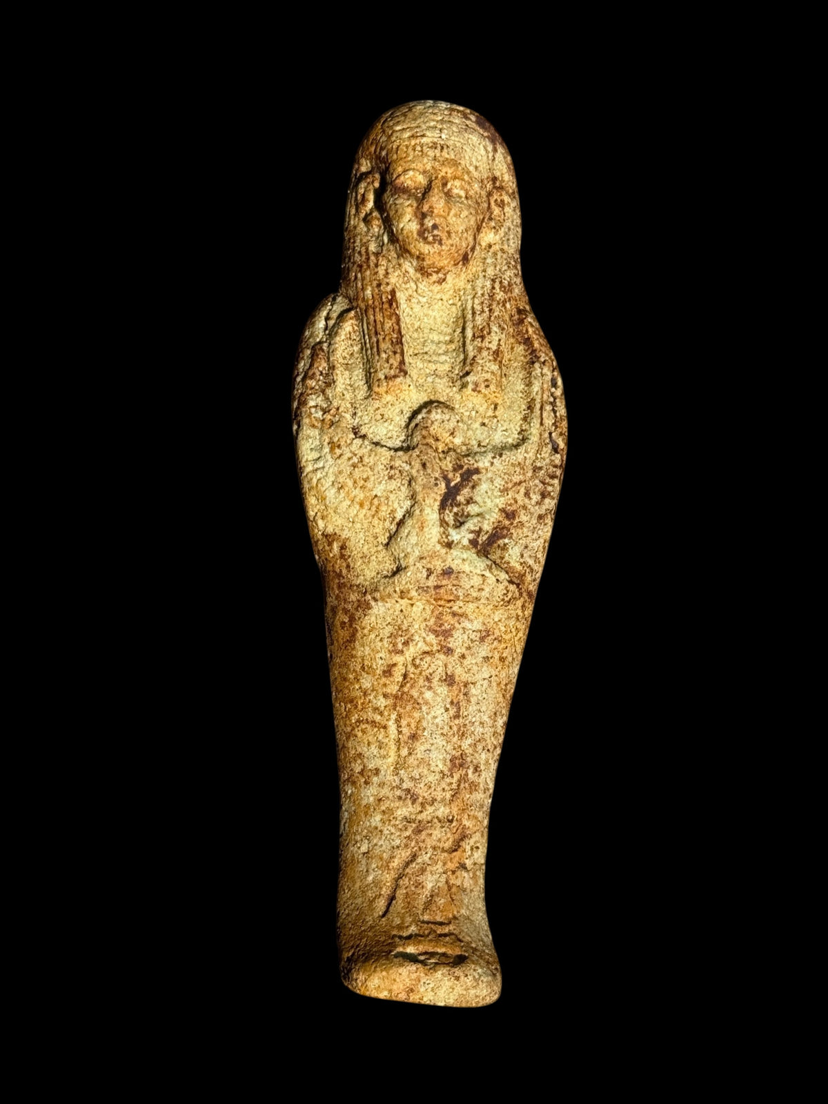 Front view of an Egyptian stone figurine featuring winged Isis, a long headdress and a textured sandy beige, brown and muted green surface.