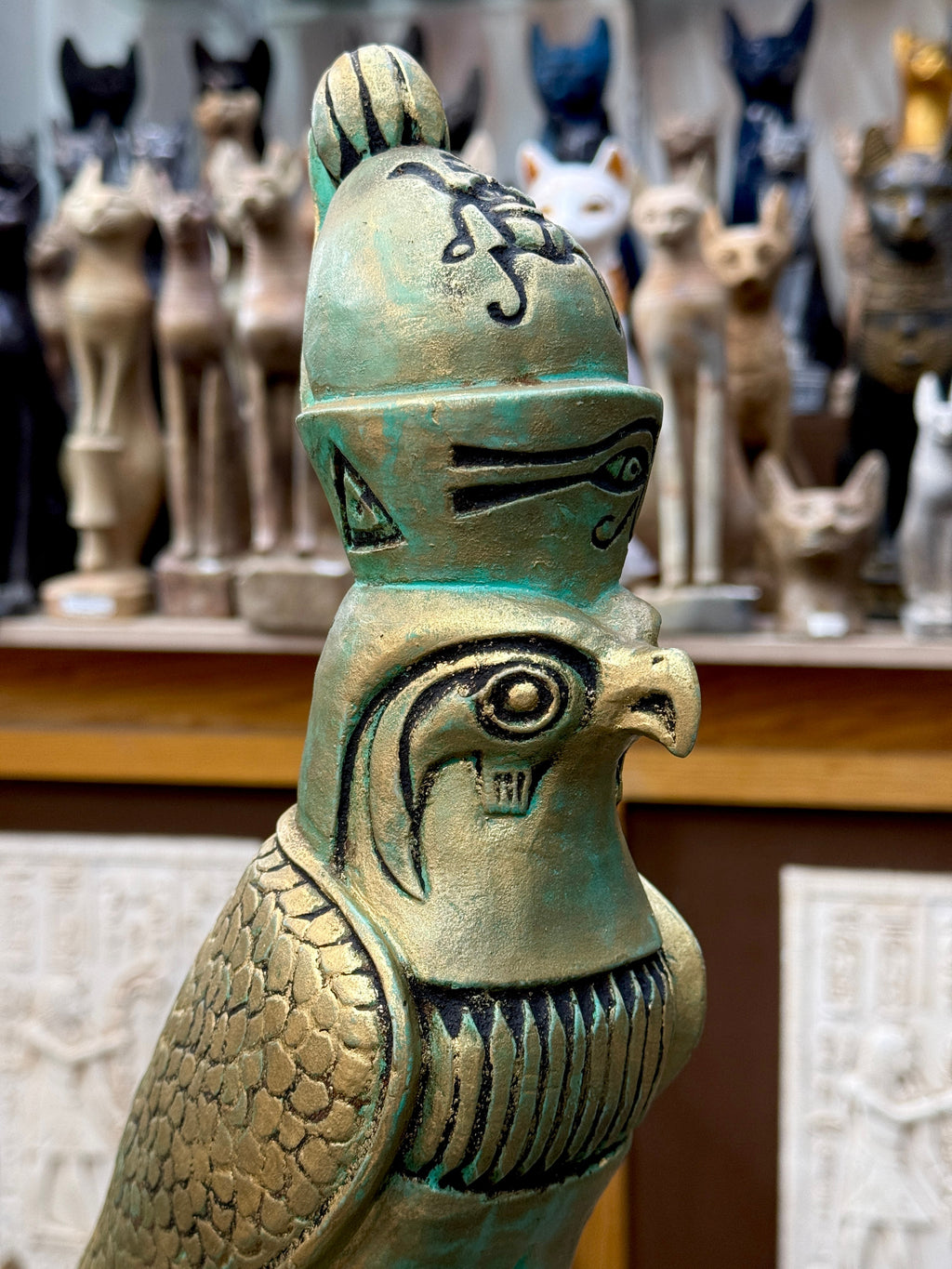 Close-up of the Horus statue’s head and crown, showing black facial markings, an eye motif, a scarab and detailed wing feathers.