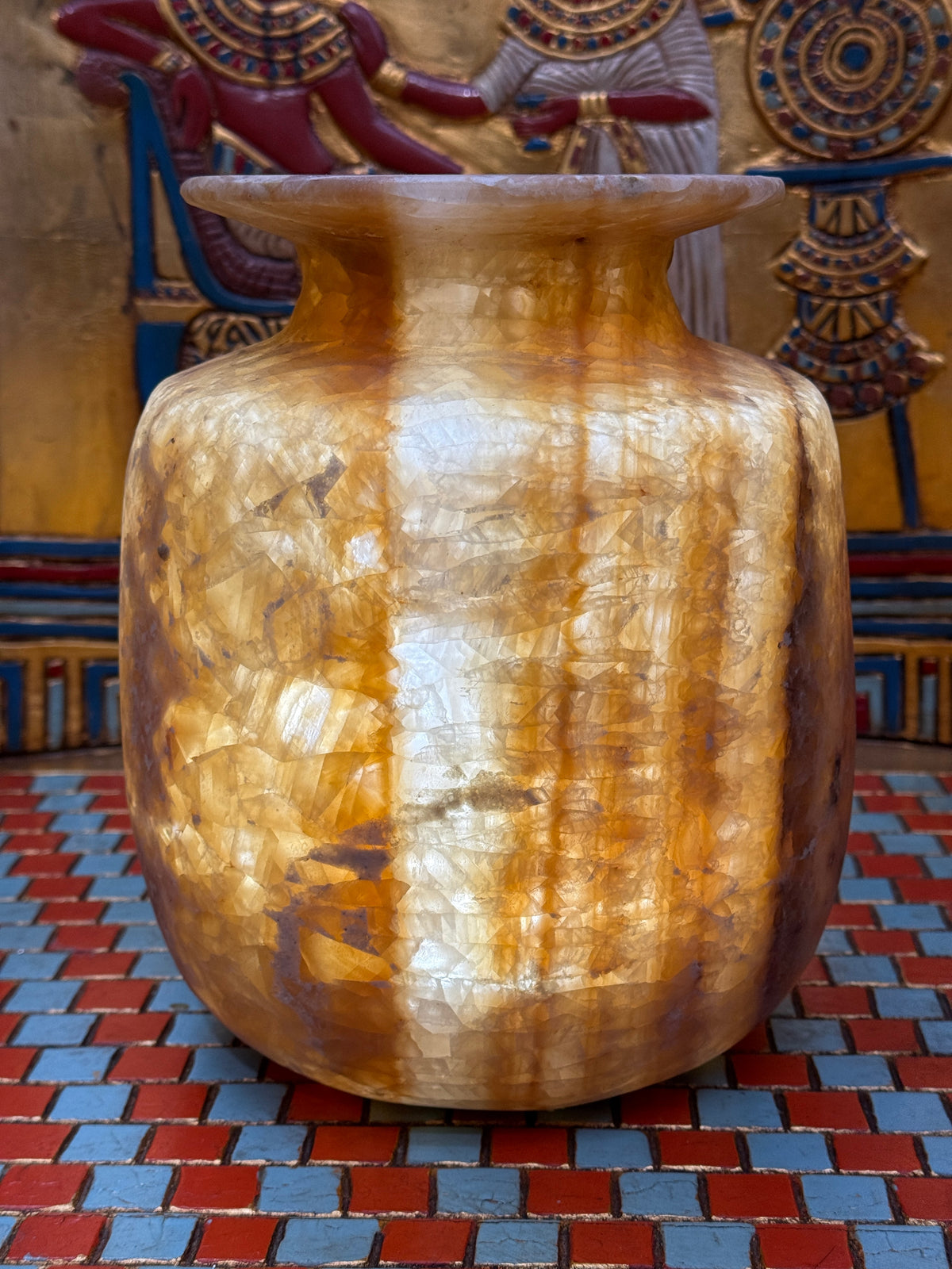 Broad alabaster vase with caramel and cream bands, rounded shoulders and a wide flared rim — illuminated view.