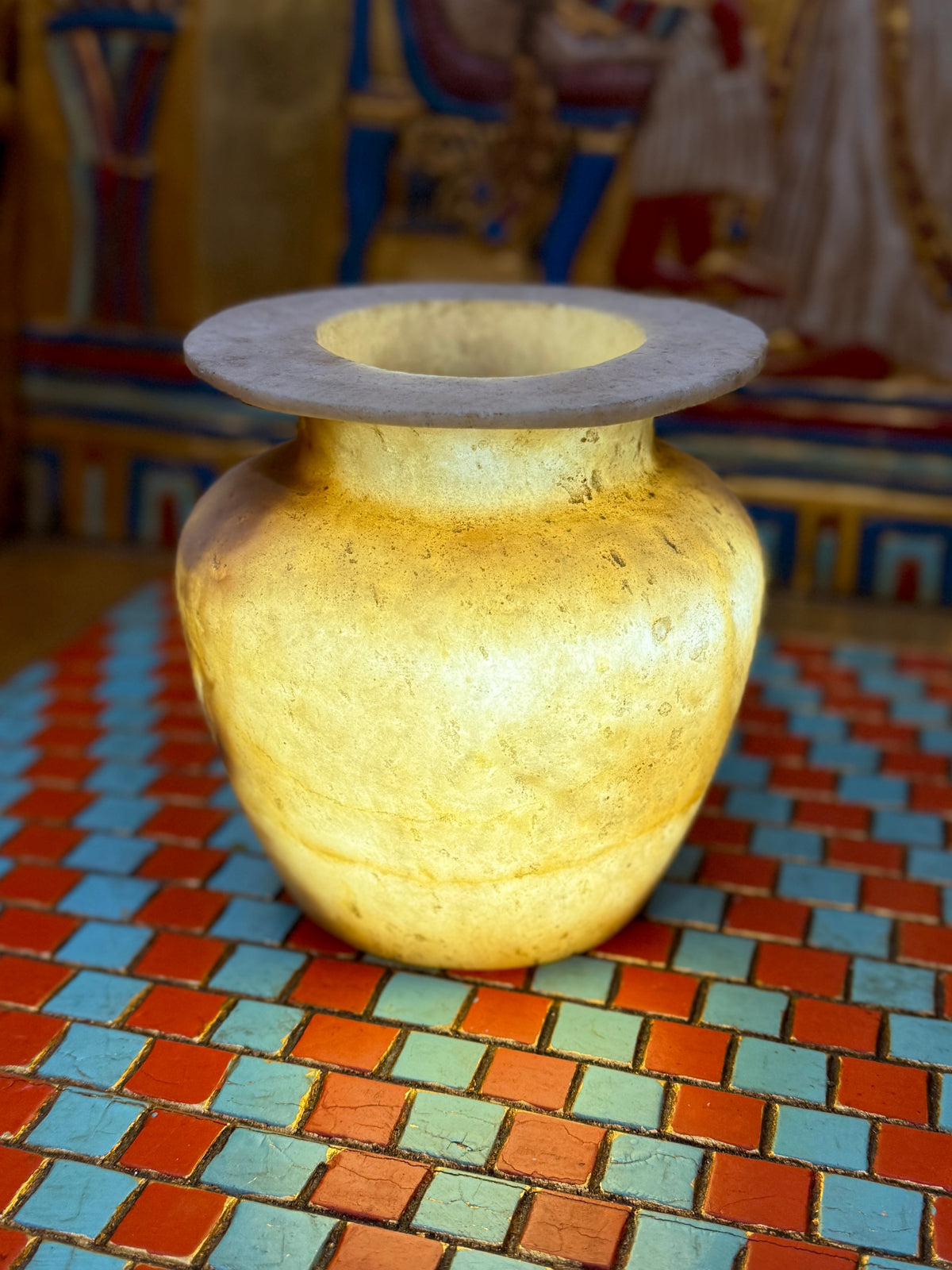 Small golden-cream alabaster vase with a rounded body, short neck and broad flared rim — full view.