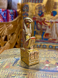 Front angled view of the gold finish Thoth kneeling statue with sculpted head, striped headdress and decorated square base.
