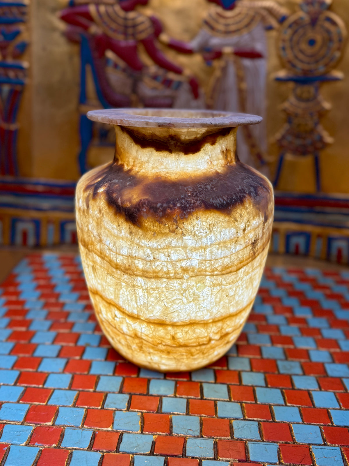 Alabaster vase with dark chestnut-coloured neck and shoulder bands, fine horizontal lines and a flared rim — illuminated view.