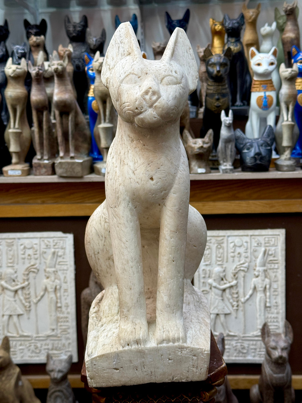 Closer front view of the seated Bastet statue showing upright ears, outlined eyes, long front legs and an integral base.